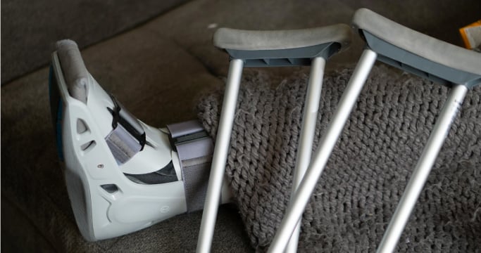 Person's leg in cast next to pair of crutches